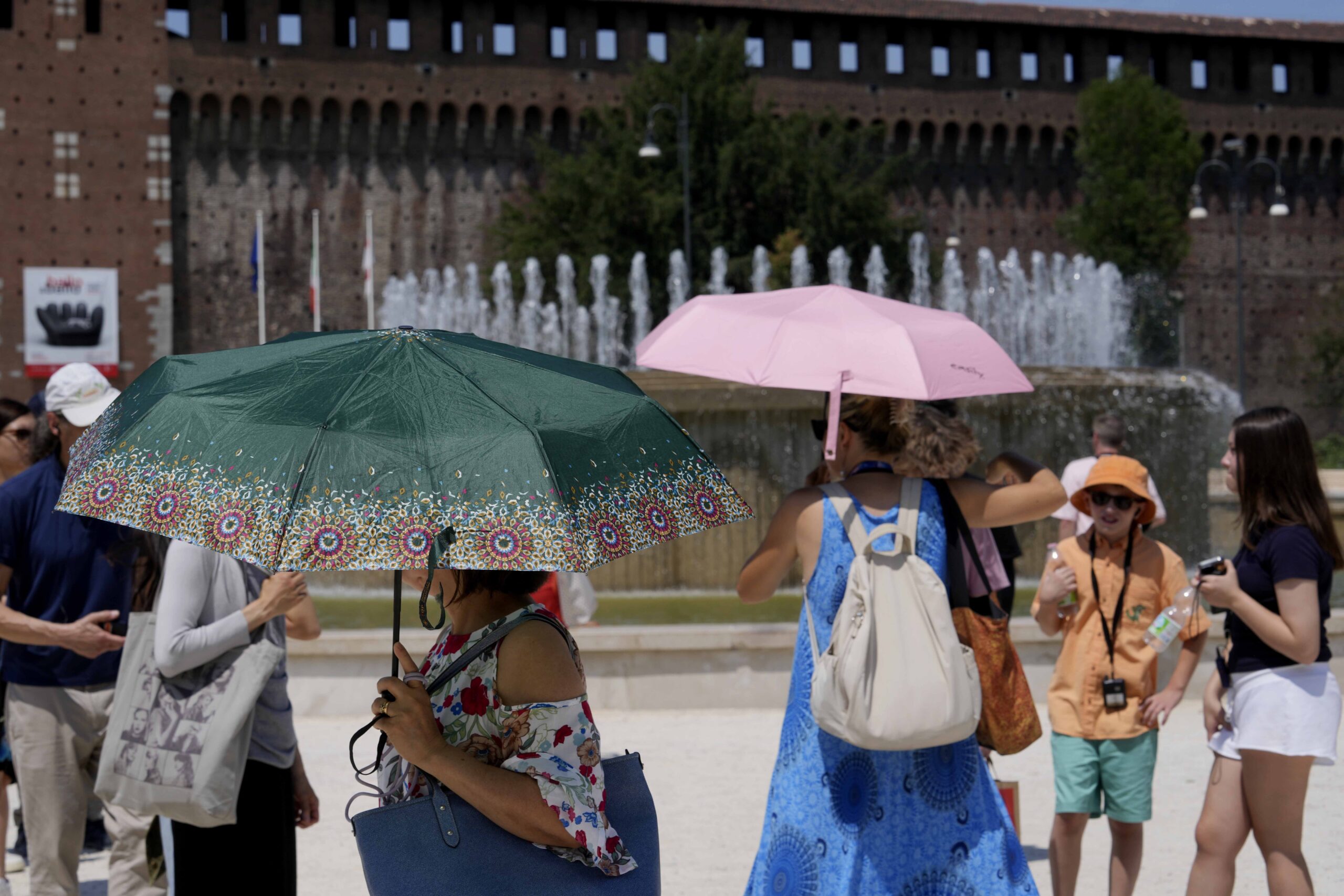 Tourists shelter from the sun in front of the Sforzesco Castle in Milan, Italy, Tuesday, July 16, 2024. Weather alerts, forest fires, melting pavement in cities: A sizzling heat wave has sent temperatures in parts of central and southern Europe soaring toward 40 degrees Celsius (104 Fahrenheit) in some places. (AP Photo/Luca Bruno)